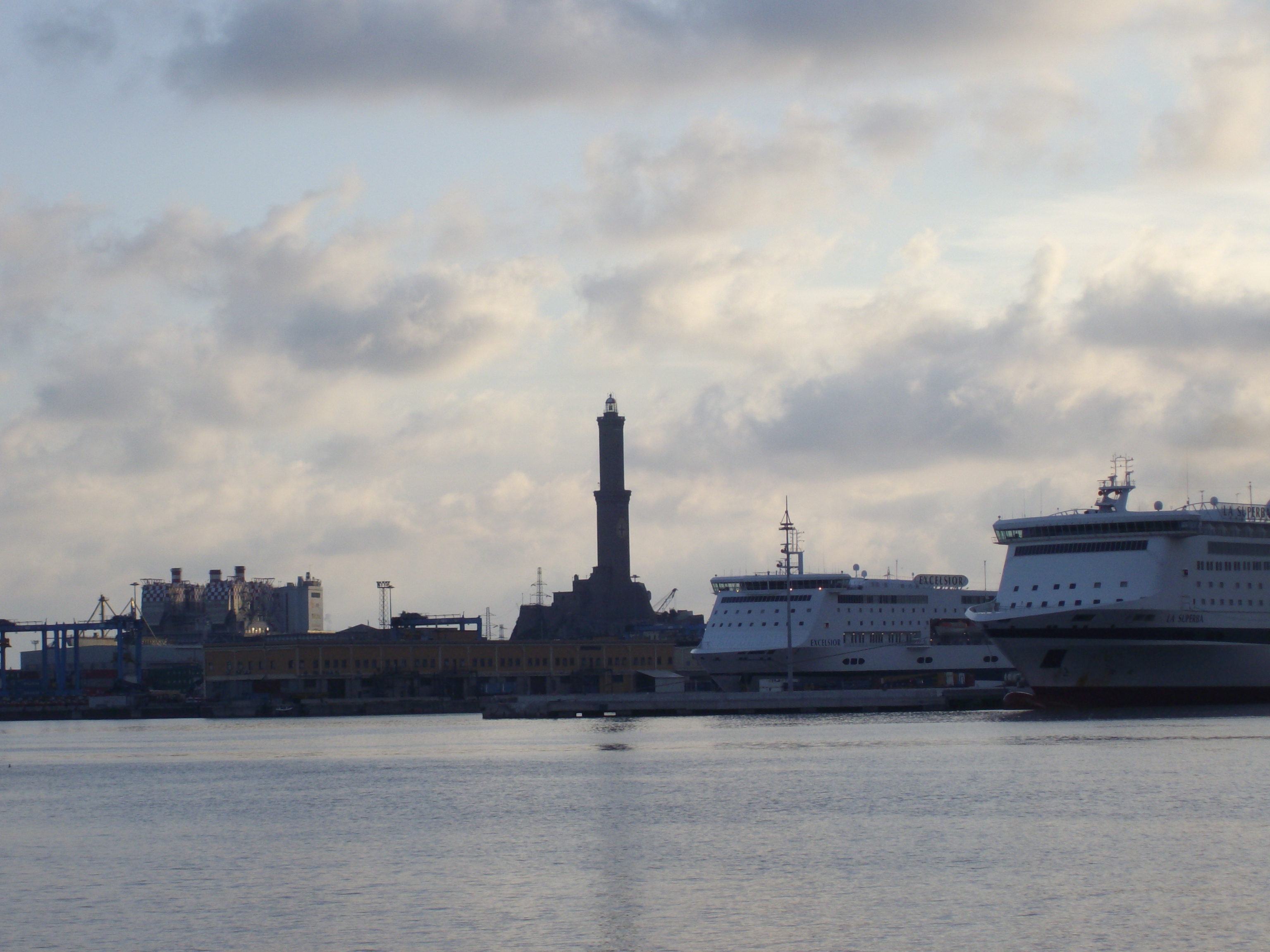 The lighthouse and cruise ships in the port of Genoa